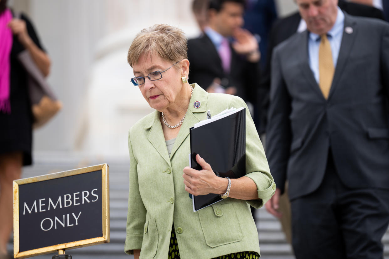 Rep. Marcy Kaptur holds a black binder in one arm while appearing to descend steps next to sign that reads: Members only.
