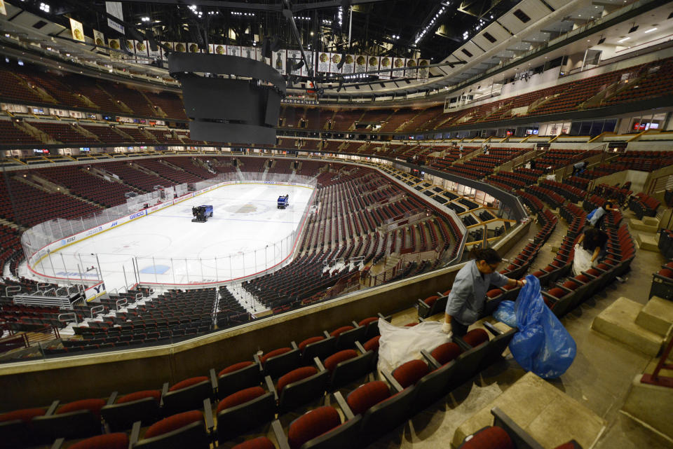Workers clean up after an NHL hockey game between the Chicago Blackhawks and the San Jose Sharks at The United Center Wednesday, March 11, 2020, in Chicago. (AP Photo/Paul Beaty)