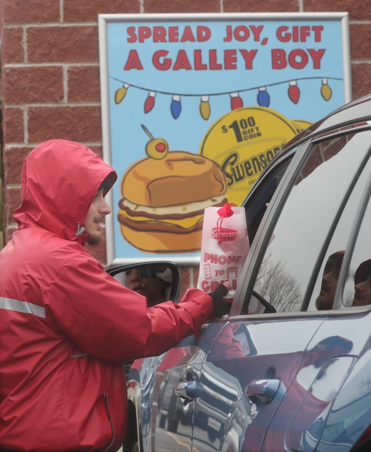 Swensons curb server Muamar Mustafa delivers an order to a car on Monday, Dec. 19, 2022, in Akron.