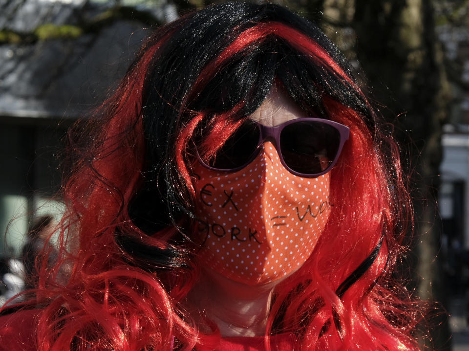 A demonstrator wears a face mask reading "sex work = work" when protesting unequal treatment and stigmatizing in The Hague, Netherlands, Tuesday, March 2, 2021. Stores in one village opened briefly, cafe owners across the Netherlands were putting tables and chairs on their outdoor terraces and sex workers demonstrated outside parliament in protests against the government's tough coronavirus lockdown. (AP Photo/Patrick Post)