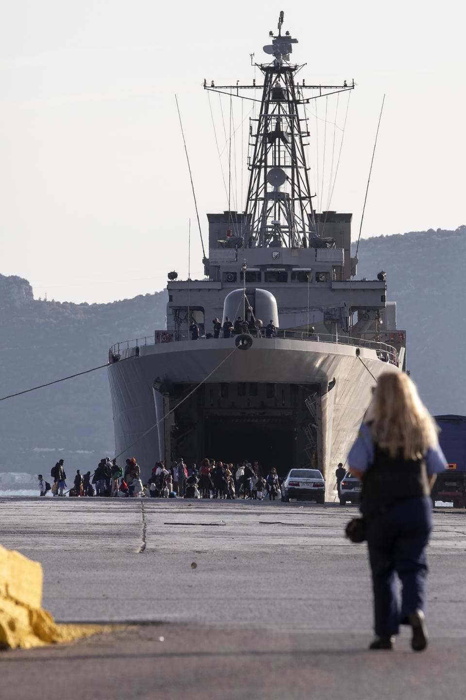 Migrants wait outside a military vessel after their disembarkation at the port of Elefsina, near Athens, on Saturday, Nov. 2, 2019. The transfer of migrants from overcrowded camps on the islands to the Greek mainland continued this weekend, with 415 arriving Saturday afternoon at the port of Elefsina west of Athens and at least another 400 expected Sunday or early Monday. (AP Photo/Yorgos Karahalis)