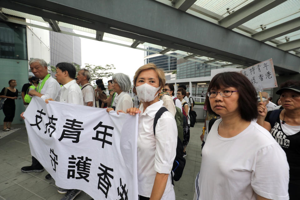 CORRECTS FIRST NAME OF THE ACTRESS - Veteran actress and singer Deanie Ip, center, wears a mask as she holds a banner in support of young people during a march in Hong Kong on Wednesday, July 17, 2019. Some 2,000 Hong Kong senior citizens, including the popular actress, marched Wednesday in a show of support for youths at the forefront of monthlong protests against a contentious extradition bill in the semi-autonomous Chinese territory.(AP Photo)