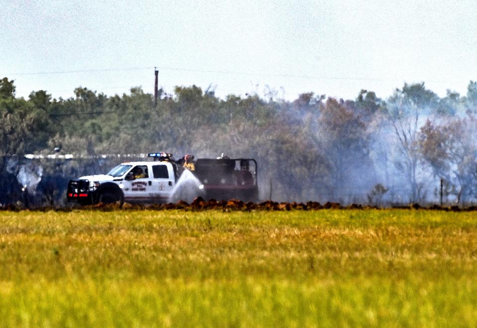 A fire crew sprays water after a grass fire reportedly burned 15 acres north of Tye, east of FM707 Wednesday July 24, 2024.