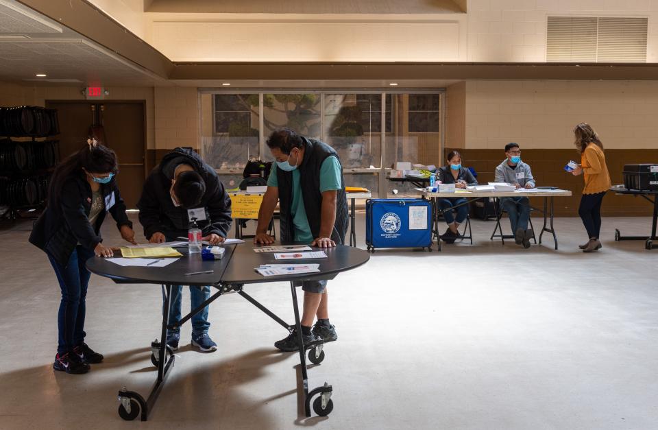 A couple of poll workers assit a Salinas voter at a polling place inside St. Mary of the Nativity Catholic ChurchÕs hall during the 2022 California Primary elections in Salinas, Calif., on Tuesday, June 7, 2022. 
