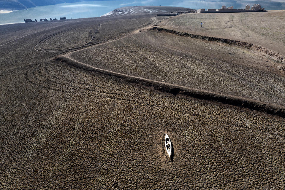 An abandoned canoe lies on the cracked ground at the Sau reservoir, which is only at 5 percent of its capacity, in Vilanova de Sau, about 100 km (62 miles) north of Barcelona, Spain, Monday, Jan. 22, 2024. Barcelona and the surrounding area of Spain's northeast Catalonia are preparing to face tighter water restrictions amid a historic drought that has shrunk reservoirs to record lows. Catalonia has recorded below-average rainfall for 40 consecutive months. Experts say that the drought is driven by climate change and that the entire Mediterranean region is forecast to heat up at a faster rate than many other regions in the coming years. (AP Photo/Emilio Morenatti)