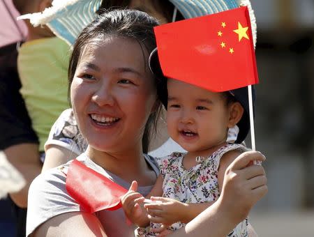 A woman and her baby wait on the street for a military parade marking the 70th anniversary of the end of World War Two, in Beijing, September 3, 2015. REUTERS/Kim Kyung-Hoon/Files