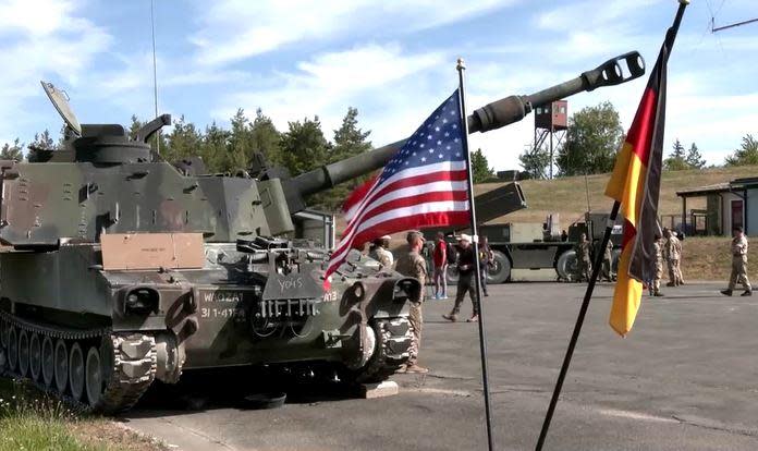 A 2022 file image shows U.S. and German flags in front of an armored fighting vehicle at the Grafenwoehr military training area in Bavaria, Germany, where U.S. troops have been training Ukrainian forces to use American weapons. / Credit: Reuters