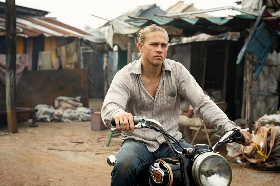 a man on a motorcycle by a slum