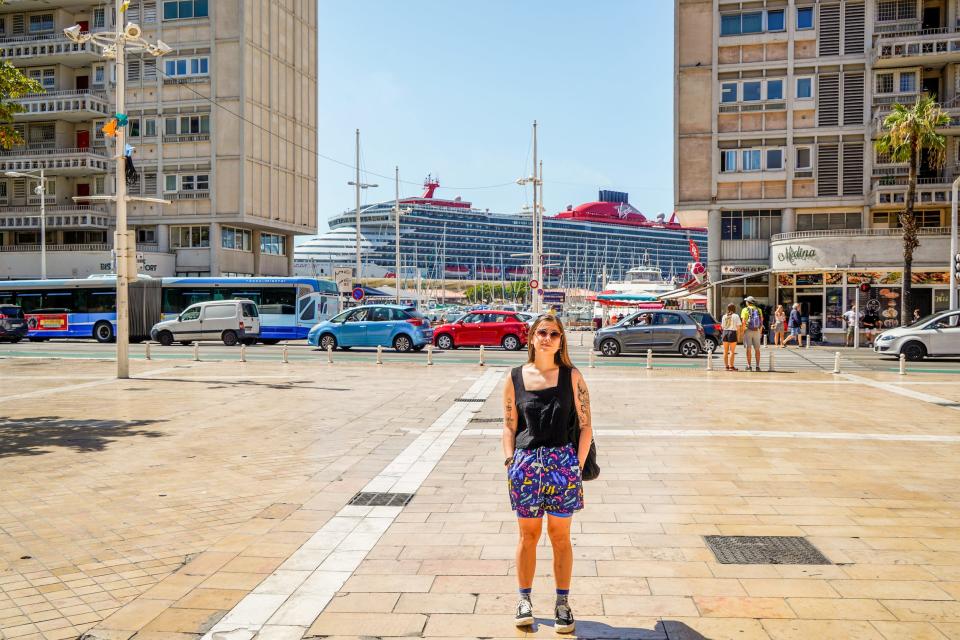 The author stands in a city with a cruise ship in the background.