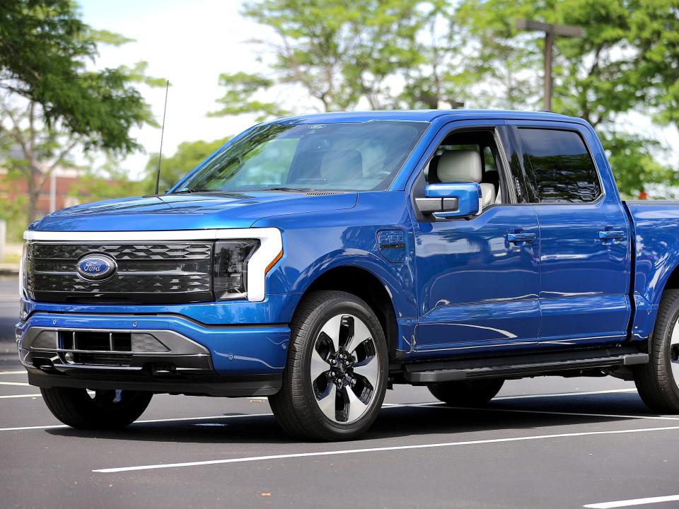 A blue Ford F-150 Lightning on a multi-lane street.