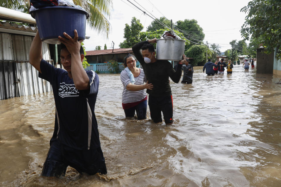 Residents wade through floodwaters carrying their belongings in the neighborhood of Suyapa, Honduras, Thursday, Nov. 5, 2020. The storm that hit Nicaragua as a Category 4 hurricane on Tuesday had become more of a vast tropical rainstorm, but it was advancing so slowly and dumping so much rain that much of Central America remained on high alert. (AP Photo/Delmer Martinez)