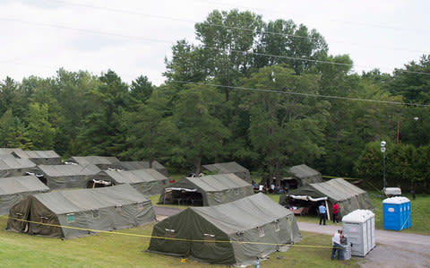 Asylum seekers are shown next to tents at the Canada-United States border in Lacolle, Quebec - Credit: Graham Hughes/The Canadian Press via AP