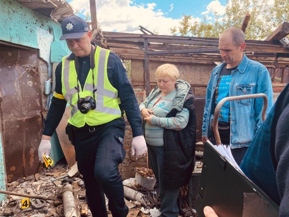 Lyudmila Yerchenko, center, leads war crimes investigators around debris in her garden left by the Russian shelling that killed her husband, in Malaya Rohan, near Kharkiv, Ukraine, May 18, 2022.  / Credit: CBS News