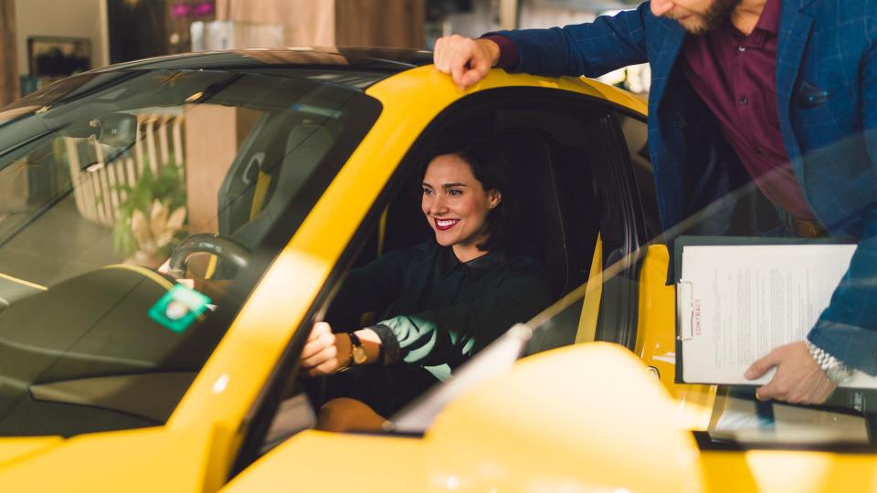Smiling woman in the showroom enjoying a car.