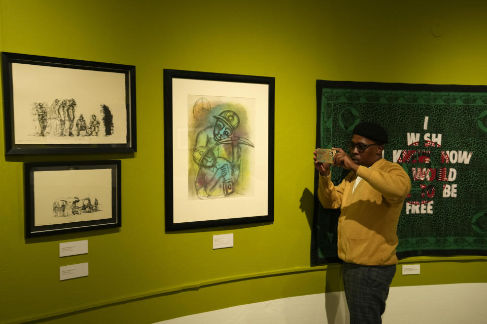 Artist Michael Selekane takes a photograph of his work at an exhibition at the Apartheid Museum in Johannesburg, South Africa, Wednesday, April 24, 2024. A selection of artworks which were produced during the country's apartheid era and ended up in foreign art collections are on display to mark 30 years since the country's transition to democracy in 1994. (AP Photo/Themba Hadebe)