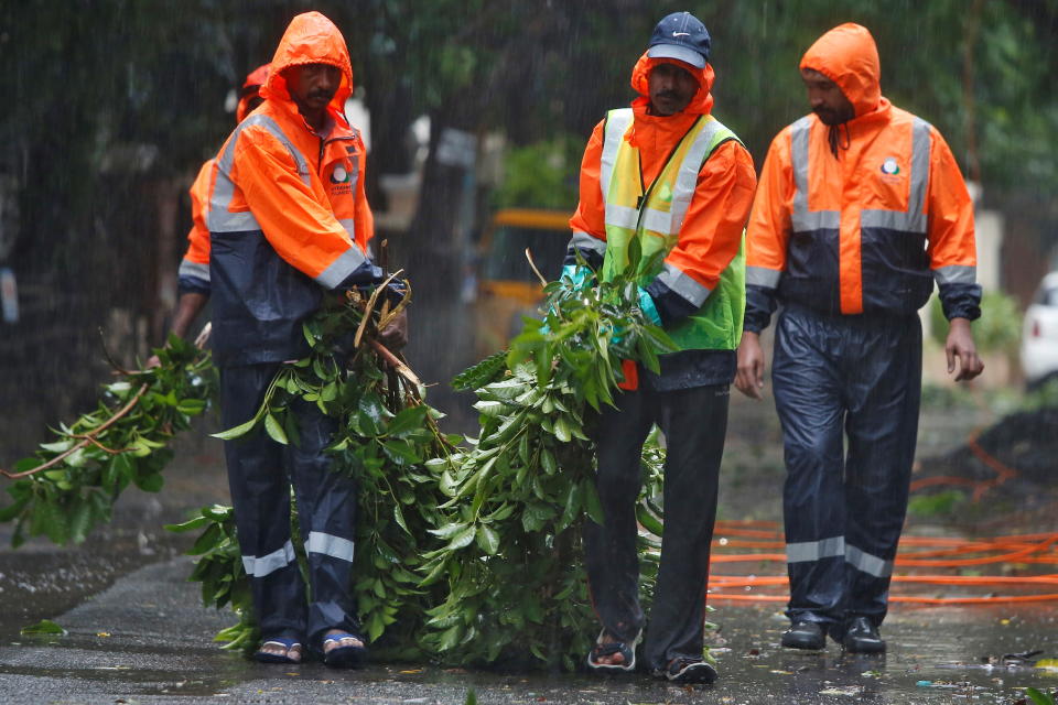 Municipal workers remove fallen tree branches from a road during rains before Cyclone Nivar's landfall, in Chennai, India, November 25, 2020. REUTERS/P. Ravikumar