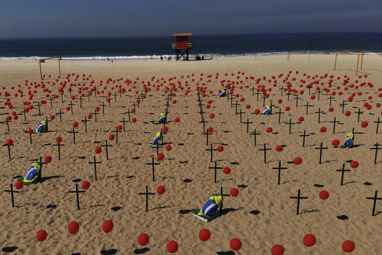 Crosses and red balloons placed in the sand on Copacabana beach to honor the victims of Covid-19: AP