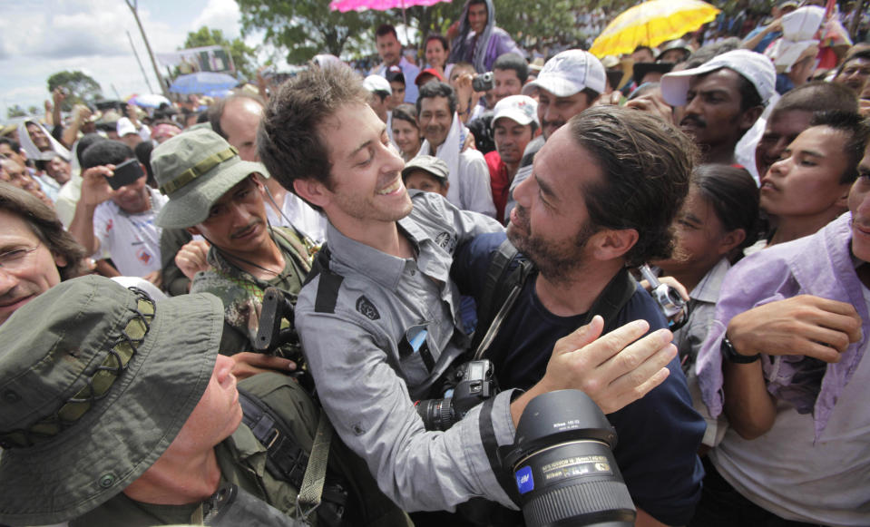 French journalist Romeo Langlois, center left, embraces fellow journalist Carlos Villalon, from Chile, in San Isidro in southern Colombia, Wednesday, May 30, 2012. Langlois, who was taken by rebels of the Revolutionary Armed Forces of Colombia (FARC) on April 28 when they attacked troops he was accompanying on a cocaine-lab eradication mission, was handed over by the rebels to a delegation that included a French diplomat. (AP Photo/Fernando Vergara)