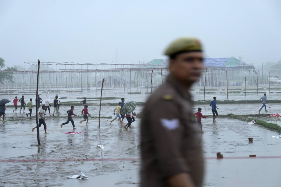 Villagers run past the site of Tuesday's stampede as it rains in Hathras district, Uttar Pradesh, India, Wednesday, July 3, 2024. Severe overcrowding and a lack of exits contributed to a stampede at a religious festival in northern India, authorities said Wednesday, leaving more than 100 people dead as the faithful surged toward the preacher to touch him and chaos ensued. (AP Photo/Rajesh Kumar Singh)