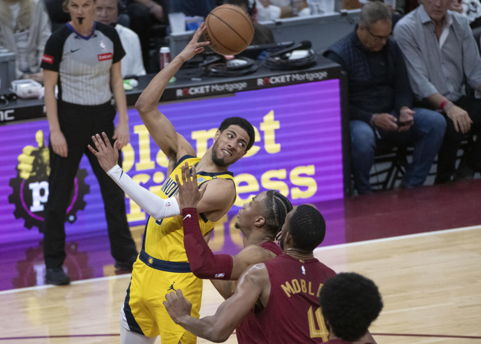 Indiana Pacers' Tyrese Haliburton, front left, looks to pass the ball as Cleveland Cavaliers' Caris LeVert, third from right, and Evan Mobley (4) defend during the first half of an NBA basketball game in Cleveland, Friday, April 12, 2024. (AP Photo/Phil Long)