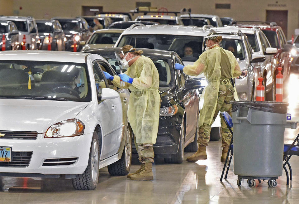 North Dakota National Guard soldiers Spc. Samantha Crabbe, left, and Master Sgt. Melanie Vincent administer COVID-19 tests, Tuesday, Nov. 17, 2020, inside the Bismarck Events Center in Bismarck, N.D. (Tom Stromme/The Bismarck Tribune via AP)