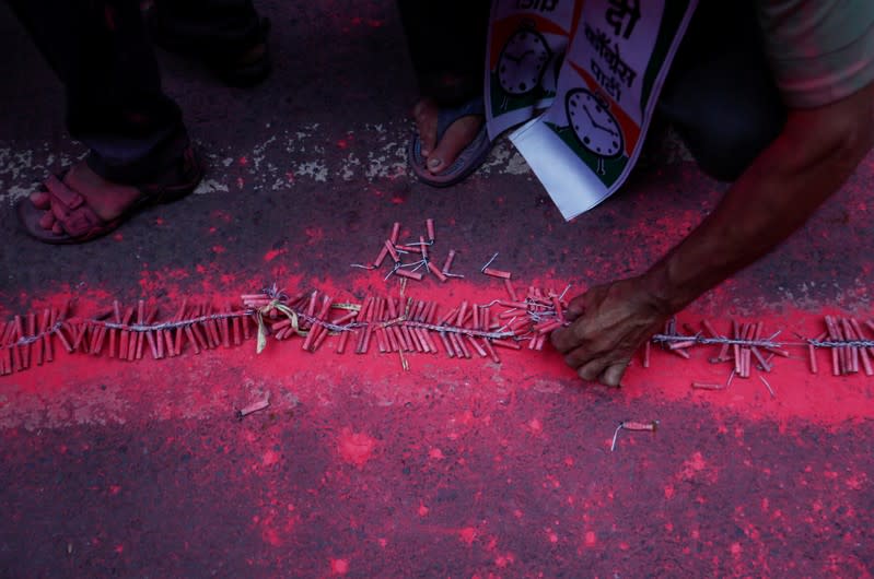 A supporter of the Nationalist Congress Party (NCP) sets up firecrackers outside the party office after learning of initial poll results in Mumbai