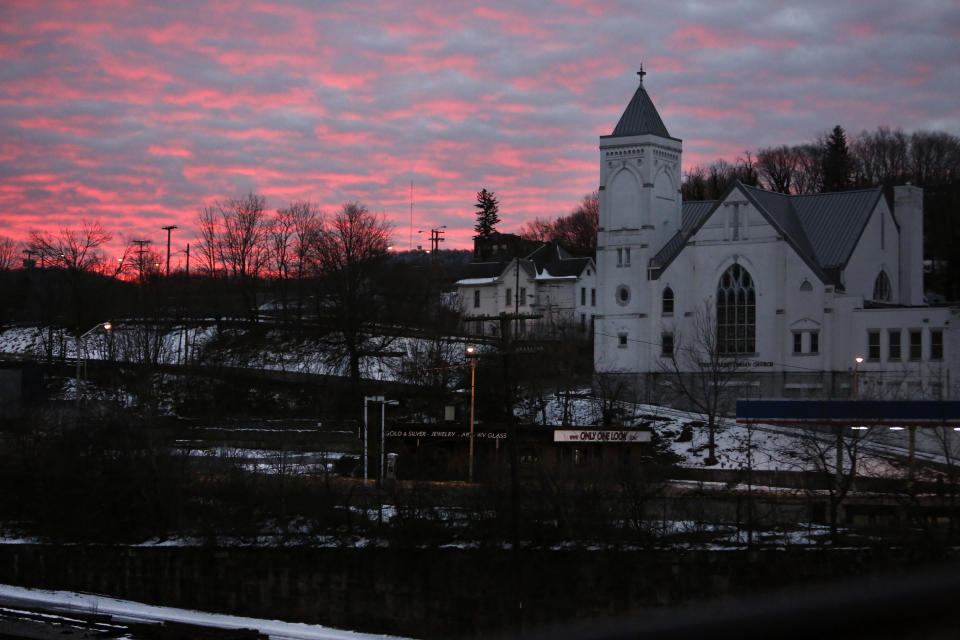 The sky lights up at dawn behind First Presbyterian Church and the rail yard in the historic coal city of Bluefield, W.Va, on Saturday, Jan. 24, 2021. Members of three congregations in a small city in West Virginia’s ‘Trump Country’ face a reckoning over Christianity and the misuse of symbols of their faith in America’s divisive politics. (AP Photo/Jessie Wardarski)