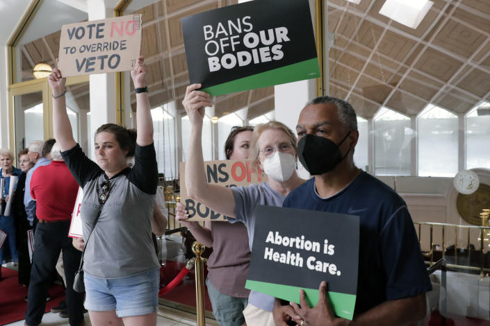 Abortion-rights supporters hold signs, Tuesday, May 16, 2023, in Raleigh, N.C., as they wait to enter the Senate gallery as state legislators debate on whether to override Democratic Gov. Roy Cooper's veto of a bill that would change the state's ban on nearly all abortions from those after 20 weeks of pregnancy to those after 12 weeks of pregnancy. Both the Senate and House had to complete successful override votes for the measure to be enacted into law. The Senate voted to override the veto. (AP Photo/Chris Seward)