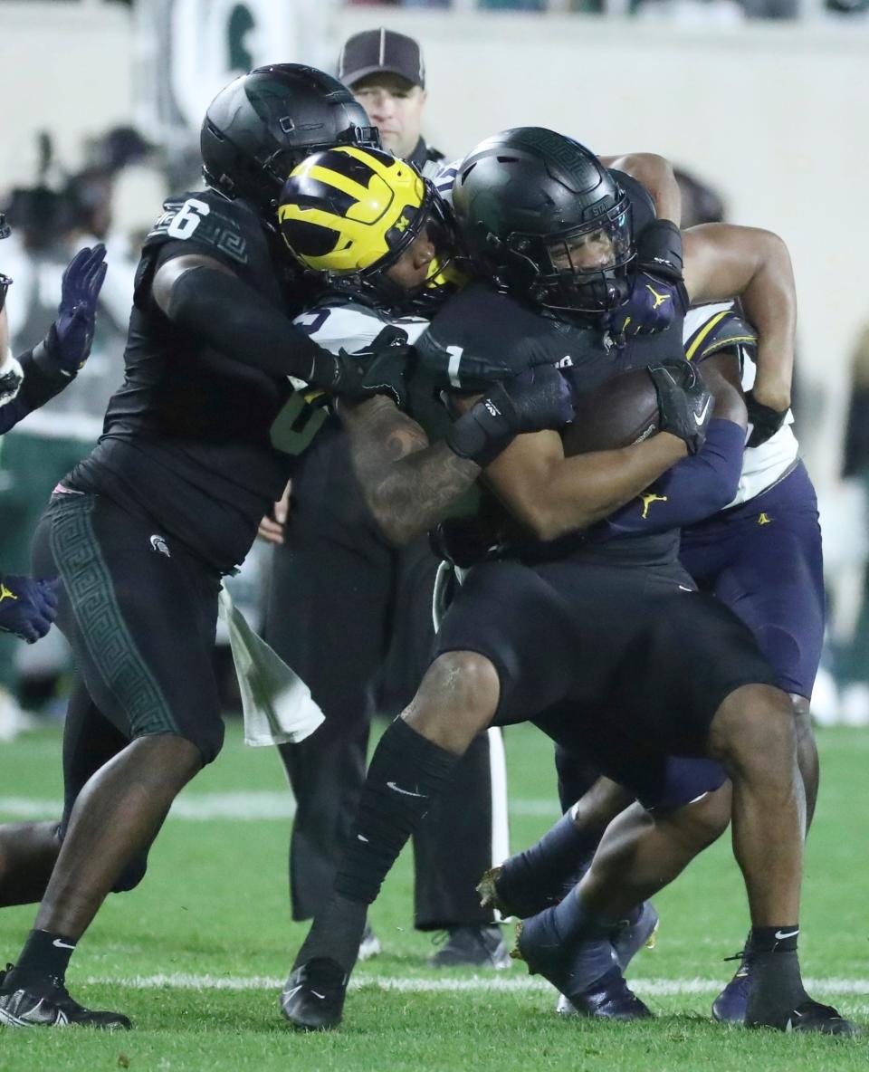 Michigan Wolverines defensive end Josaiah Stewart (5) tackles Michigan State Spartans running back Nathan Carter (5) during second-half action at Spartan Stadium in East Lansing on Saturday, Oct. 21, 2023.