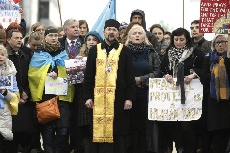 An orthodox priest stands amidst Ukrainian protesters, outside the European Council building in Brussels, Thursday, Feb. 20, 2014. The 28-nation European Union is to hold an emergency meeting on Ukraine, to consider sanctions against those behind the violence. (AP Photo/Yves Logghe)