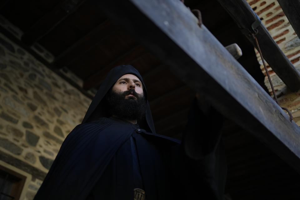 A monk uses a mallet on a plank to summon monks and visitors to the afternoon prayers at the Pantokrator Monastery in the Mount Athos, northern Greece, on Thursday, Oct. 13, 2022. Deep inside a medieval fortified monastery in the Mount Athos monastic community, researchers are for the first time tapping a virtually unknown treasure: thousands of Ottoman-era manuscripts that include the oldest of their kind in the world. (AP Photo/Thanassis Stavrakis)