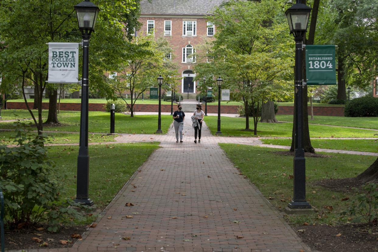 Two Ohio University students walk through the college green in Athens in 2020. Ohio University is reinstating its mask mandate because Athens County is listed as having a high level of transmission on the Centers for Disease Control and Prevention's latest COVID-19 data tracker.