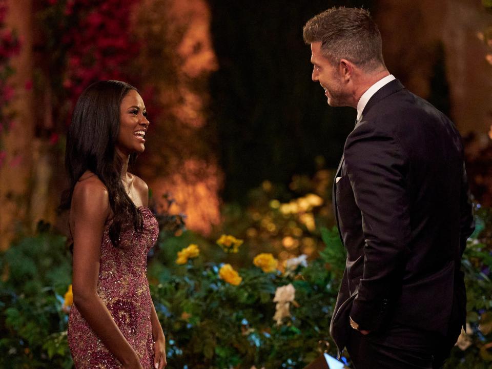 Charity Lawson, in a purple beaded gown, stands talking to "Bachelorette" host Jesse Palmer, in a suit.