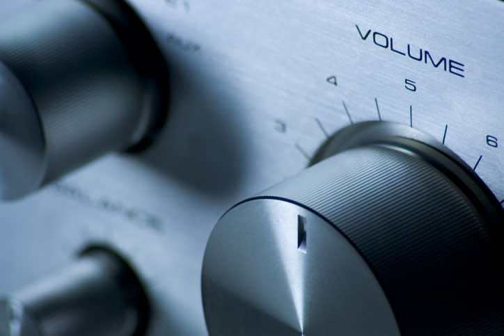 Close-up of a stereo system's volume control knob, set to a medium level, reading "Volume." Other control knobs are partially visible