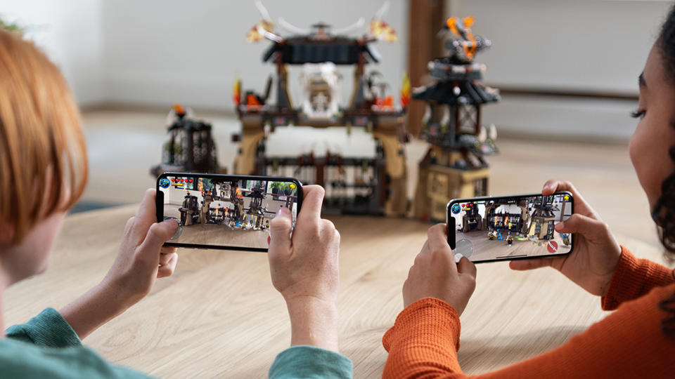 Two people viewing a toy castle through their iPhones.