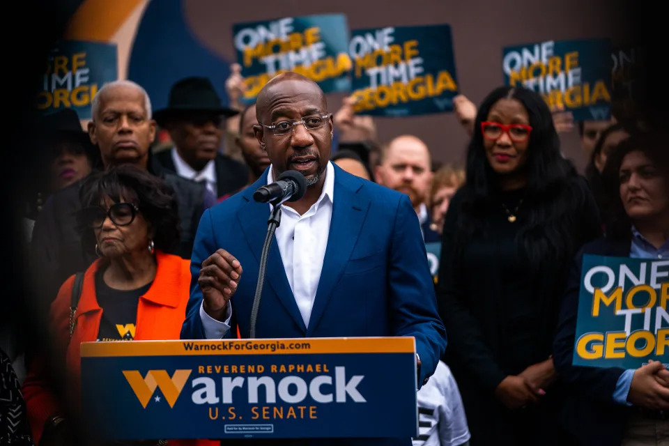 Sen. Raphael Warnock, D-Ga., speaks to supporters, some of whom hold signs reading: One More Time Georgia.