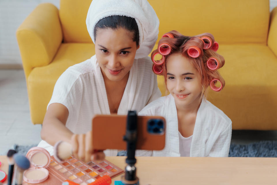 A mommy vlogger taking photos with her child doing their hair and makeup
