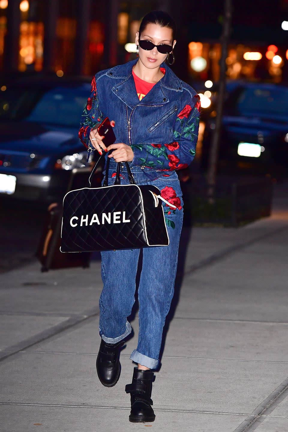 <p>In red t-shirt under an embroidered Adam Selman moto jacket with matching jeans, a Chanel duffel bag, Dr. Martens boots and black sunglasses while out in New York City. </p>