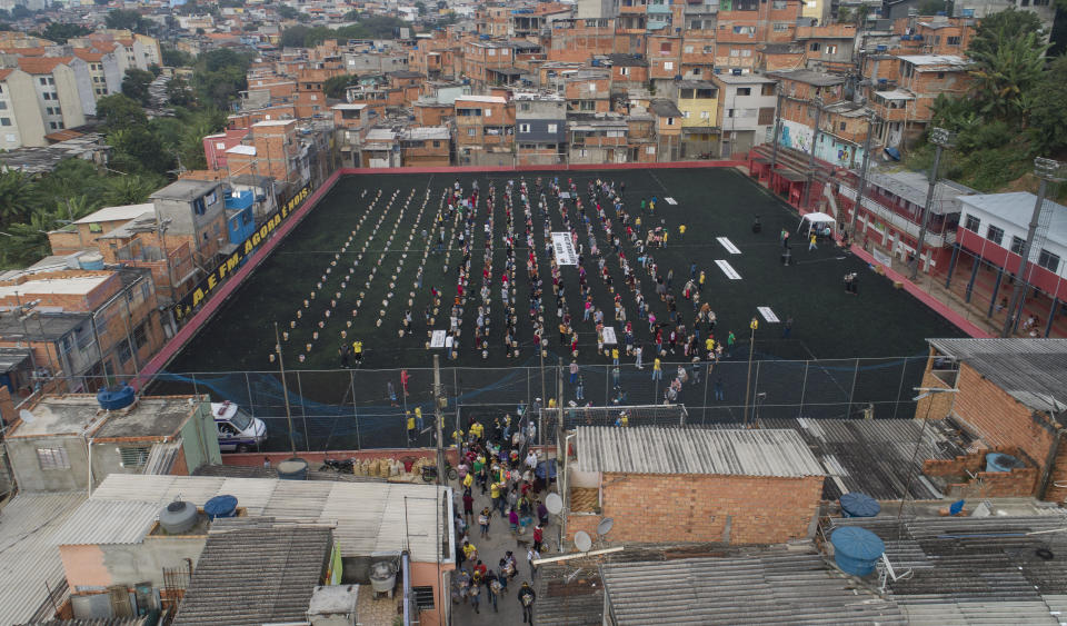 FILE - In this April 26, 2021 file photo, residents wait on a soccer field for food donated by the local NGO "G10 Favelas," amid the COVID-19 pandemic in the Capao Redondo area of Sao Paulo, Brazil. In the first quarter of 2021, Brazil saw its highest unemployment and economic inequality in at least nine years, with the cost of living surging and tent cities and shantytowns emerging. (AP Photo/Andre Penner, File)