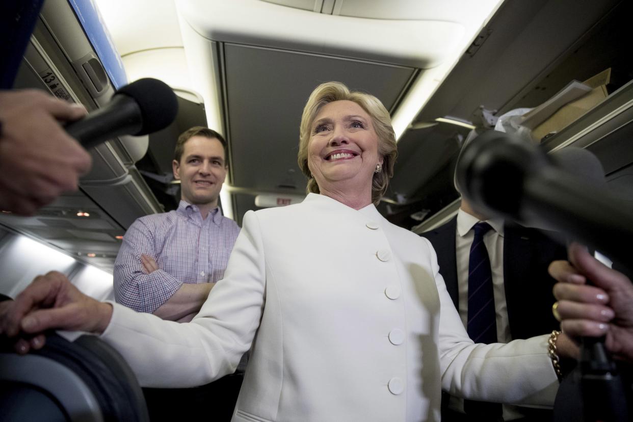Democratic presidential candidate Hillary Clinton, center, accompanied by Campaign Manager Robby Mook, left, and traveling press secretary Nick Merrill, right, smiles as she speaks with members of the media aboard her campaign plane at McCarran International Airport in Las Vegas, Wednesday, Oct. 19, 2016, following the third presidential debate. (Photo: Andrew Harnik/AP)