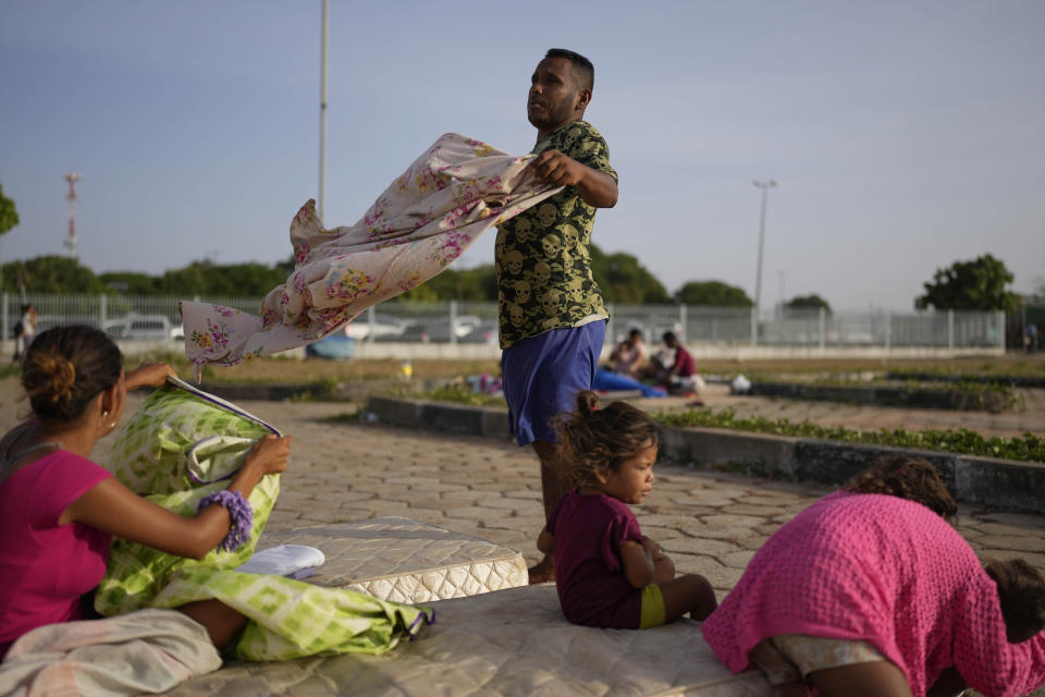 Venezuelan migrant Carlos Hernandez arranges his things with his family after sleeping outdoors in the parking lot of a bus terminal in Boa Vista, Roraima state, Brazil, Friday, April 7, 2023. (AP Photo/Matias Delacroix)
