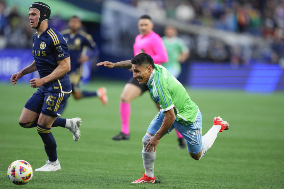 Seattle Sounders forward Raúl Ruidíaz loses his footing as he runs for the ball against Vancouver Whitecaps defender Bjorn Inge Utvik, left, during the first half of an MLS soccer match Saturday, April 20, 2024, in Seattle. (AP Photo/Lindsey Wasson)