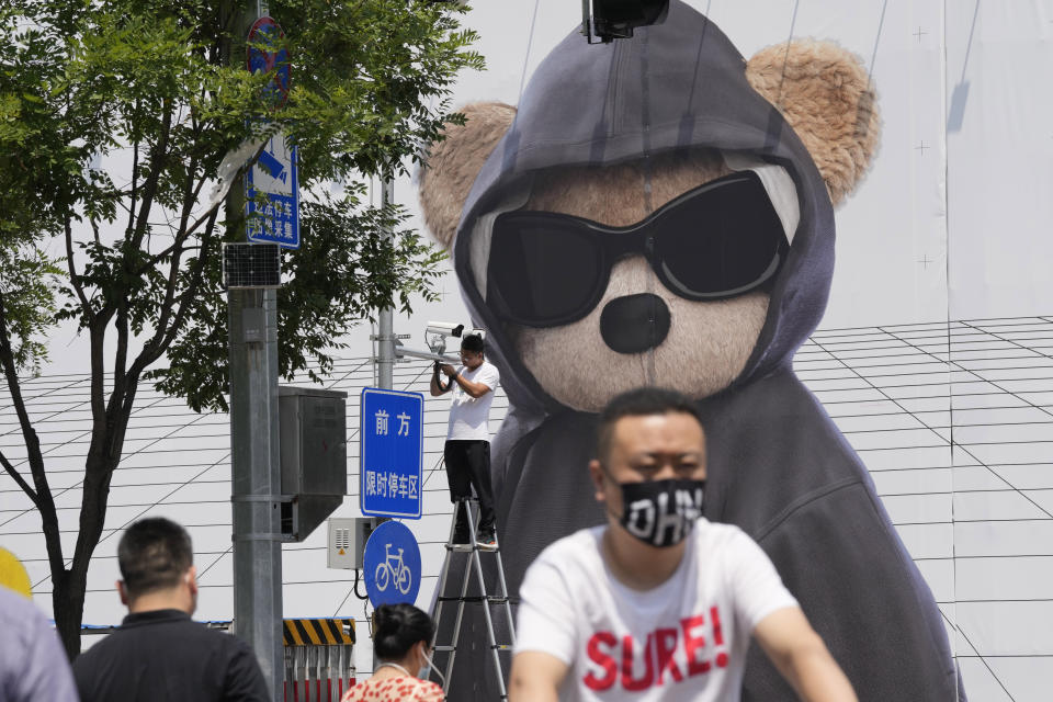 A worker installs a surveillance camera outside a mall, Friday, July 8, 2022, in Beijing. China's economic growth plunged to 0.4% over a year earlier in the latest quarter after Shanghai and other cities were shut down to fight coronavirus outbreaks, but the government said a "stable recovery" is underway. (AP Photo/Ng Han Guan)