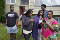 From left, Kevin Mugisha, Guillin Mugabo Toto, Sada Batamuriza, Kevine Uwase, Patrick Bizima, and Emmerence Mugeni stand in the yard of the home they share with their father, Wednesday, Oct. 14, 2020, and look at photos of their mother, Ziporah Nyirahimbya, who is in Uganda and has been unable so far to join them in the U.S. For decades, America admitted more refugees annually than all other countries combined, but that reputation has eroded during Donald Trump's presidency as he cut the number of refugees allowed in by more than 80 percent. (AP Photo/Ted S. Warren)