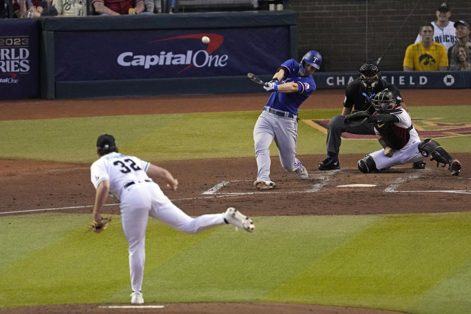 Texas Rangers' Corey Seager, center, hits a two-run home run off Arizona Diamondbacks starting pitcher Brandon Pfaadt (32) during the third inning in Game 3 of the baseball World Series Monday, Oct. 30, 2023, in Phoenix. (AP Photo/Ross D. Franklin)