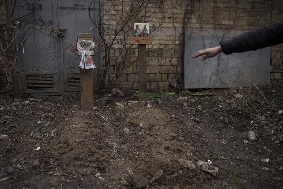 A witness gestures next to the grave of two civilians buried in a backyard in Bucha, on the outskirts of Kyiv, Ukraine, Wednesday, April 6, 2022. (AP Photo/Felipe Dana)