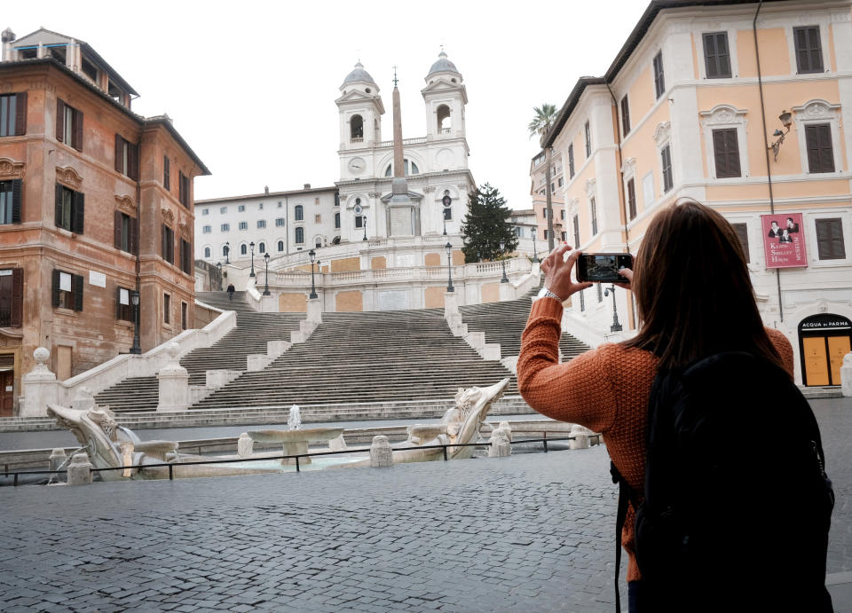 A woman takes photos of The Spanish Steps in Rome Friday, March 13, 2020. A sweeping lockdown is in place in Italy to try to slow down the spread of coronavirus epidemic. For most people, the new coronavirus causes only mild or moderate symptoms. For some, it can cause more severe illness, especially in older adults and people with existing health problems. (Mauro Scrobogna/LaPresse via AP)