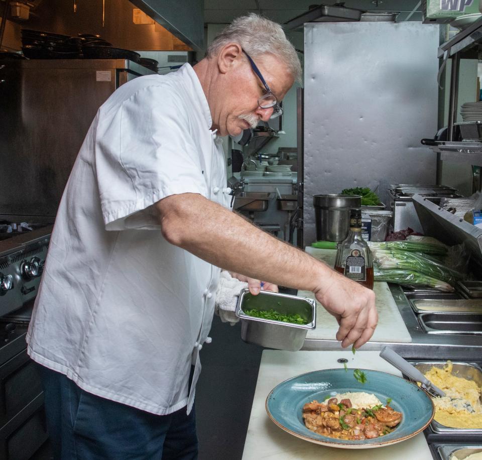 Chef Gregg McCarthy garnishes an order of shrimp and grits at the Grand Marlin in Pensacola Beach on Thursday, May 19, 2022.  McCarthy will be one of four renowned chefs who will be participating in the G&G Seafood Rodeo.