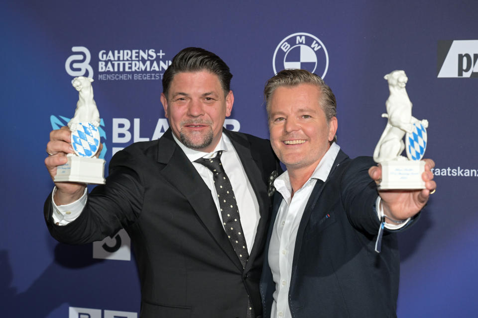 Tim Mälzer und André Dietz beim Blauer Panther TV & Streaming Awards 2023 in der BMW Welt in München, beide halten ihren Award in die Kamera und lachen 