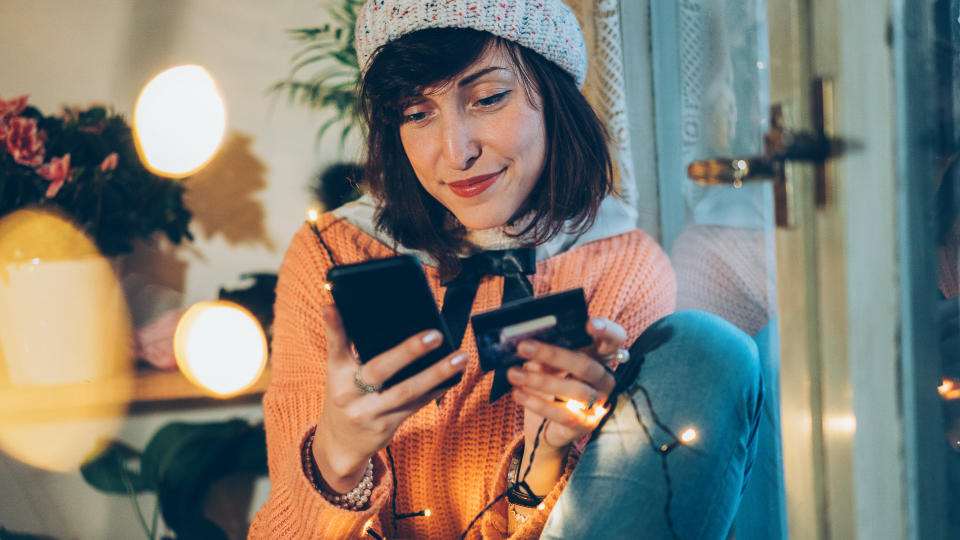 Beautiful woman shopping onlain using smartphone and debit card.